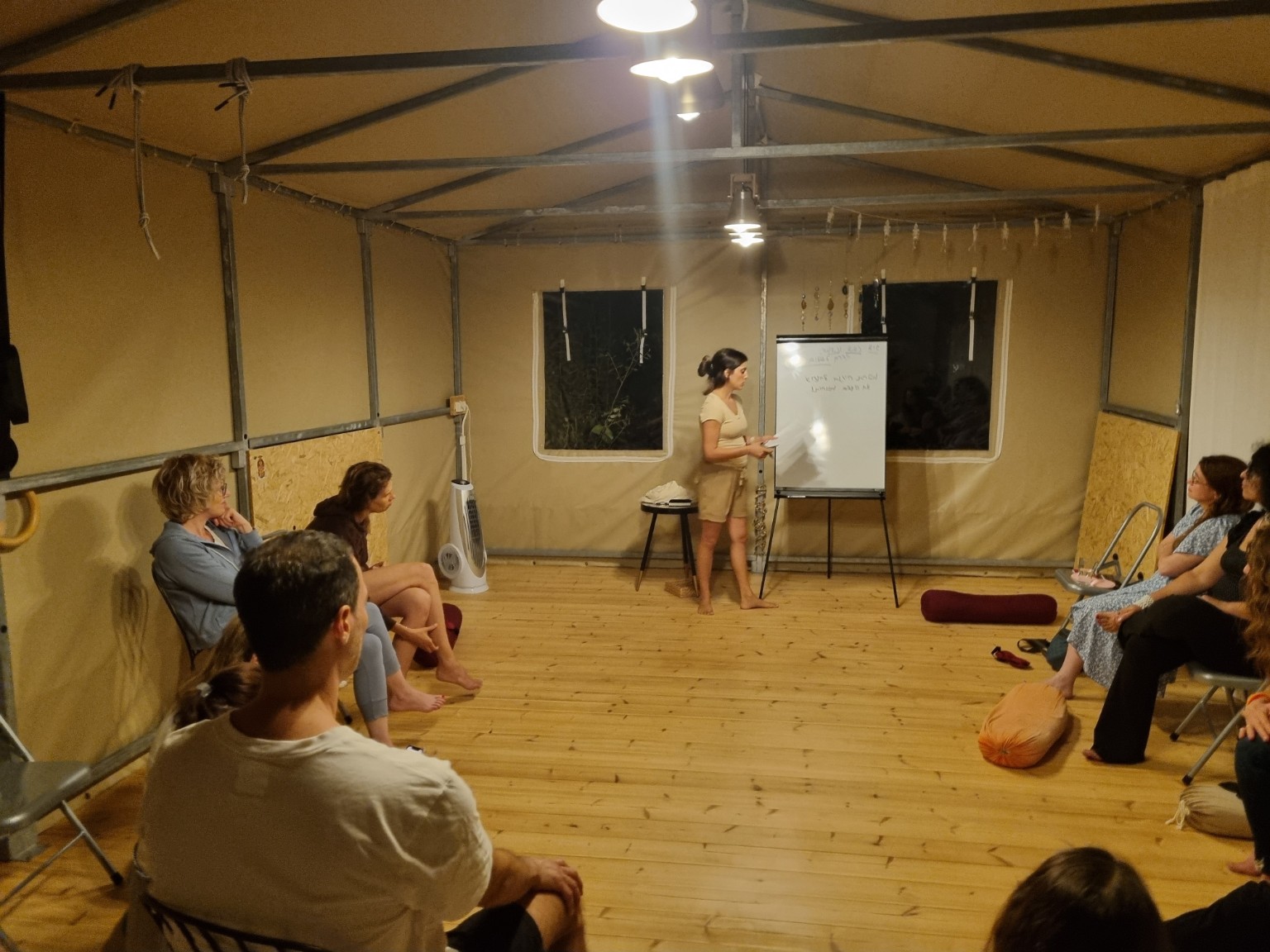 מאיה מנחה שיחה עם משתתפים היושבים במעגל בסטודיו