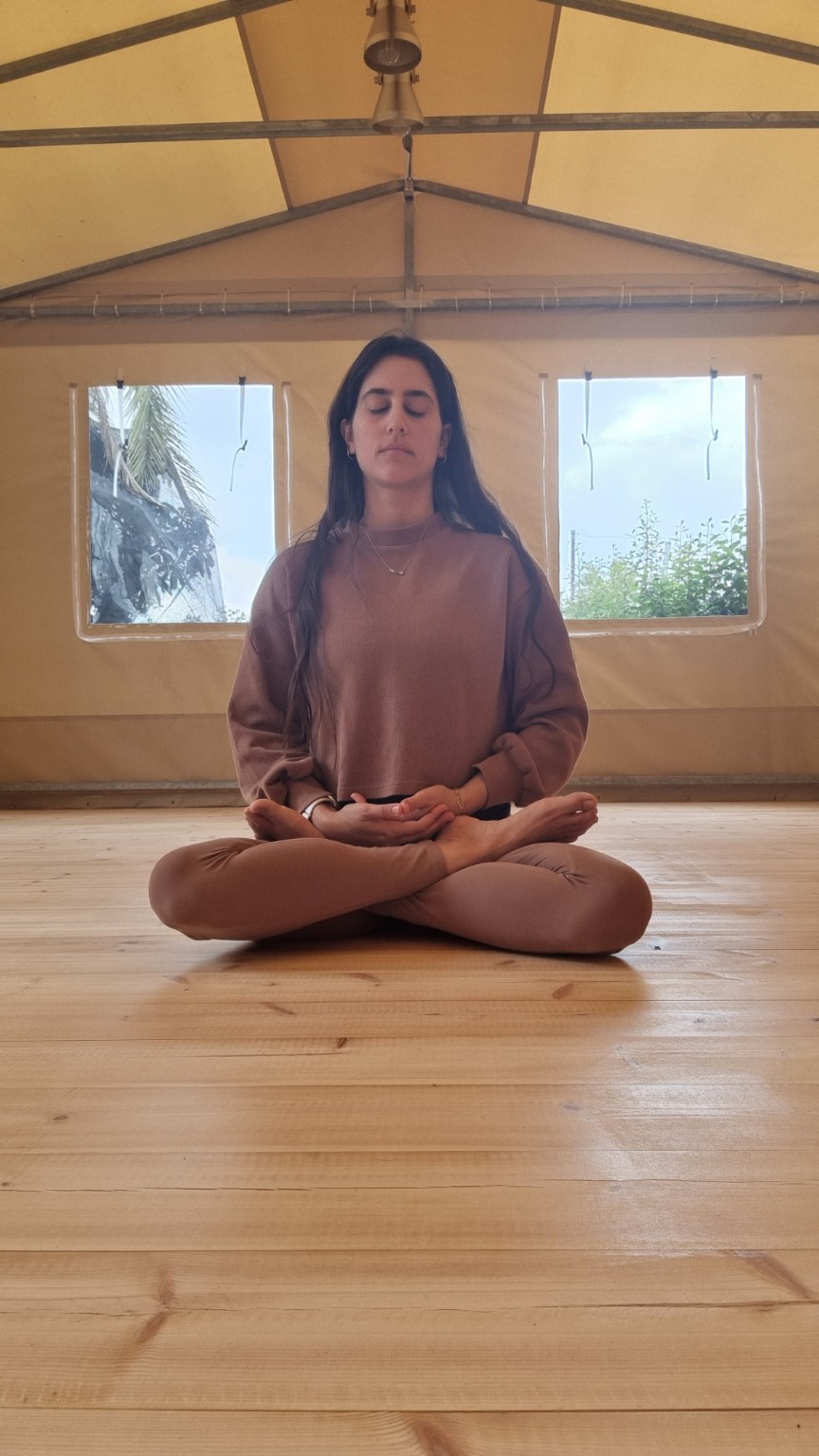 מאיה יושבת במדיטציה בסטודיו, בעיניים עצומות